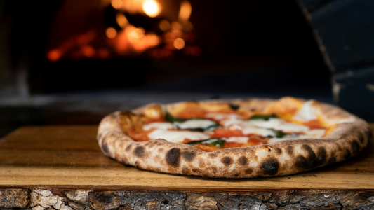 Charred Margarita pizza sitting by a flaming oven